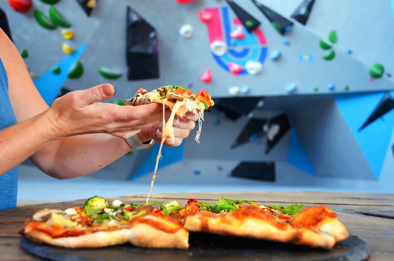 A slice of pizza being lifted from the tray, the wall behind