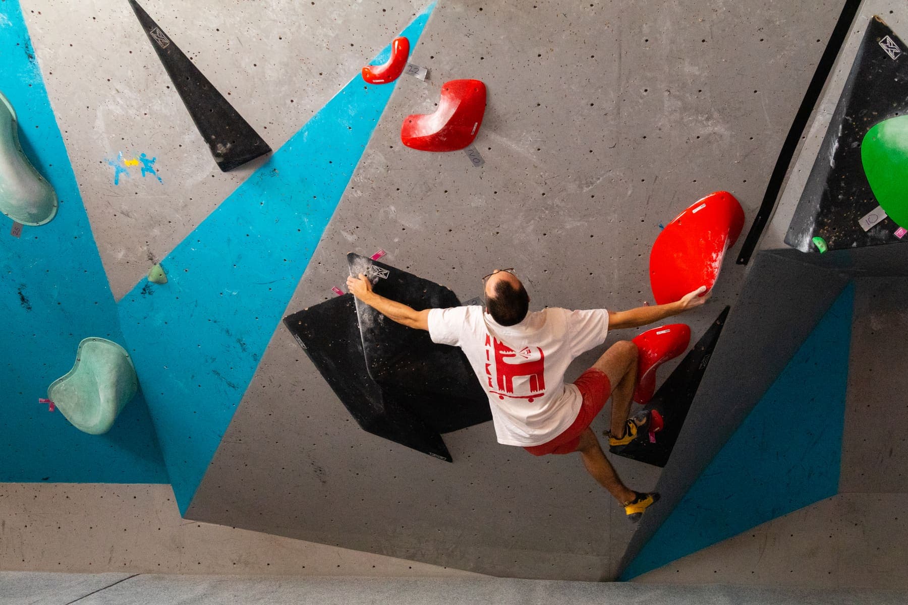 A climber seen from above on a steep blue and grey wall