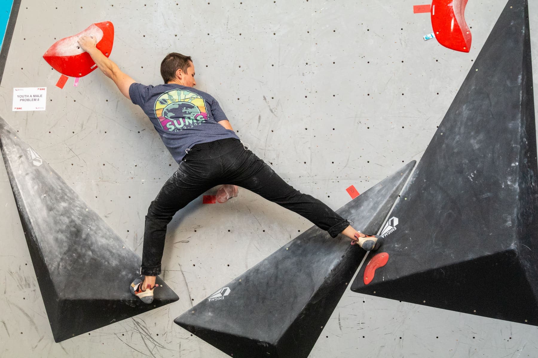 A climber spread wide between two black volumes