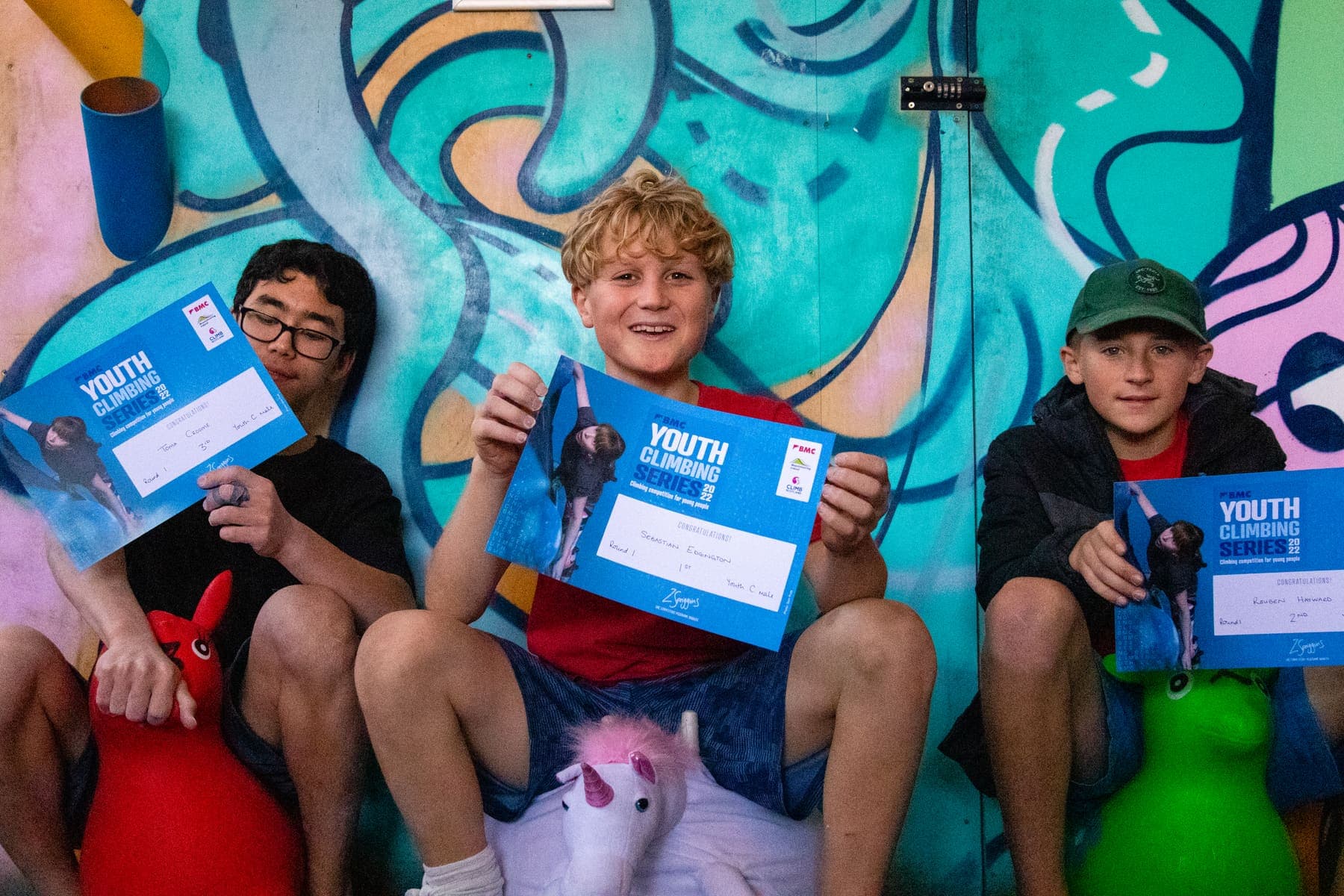 Three young climbers grinning with their certificates